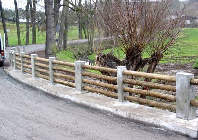 Barriere aus Rundholz zwischen Betonstehlen